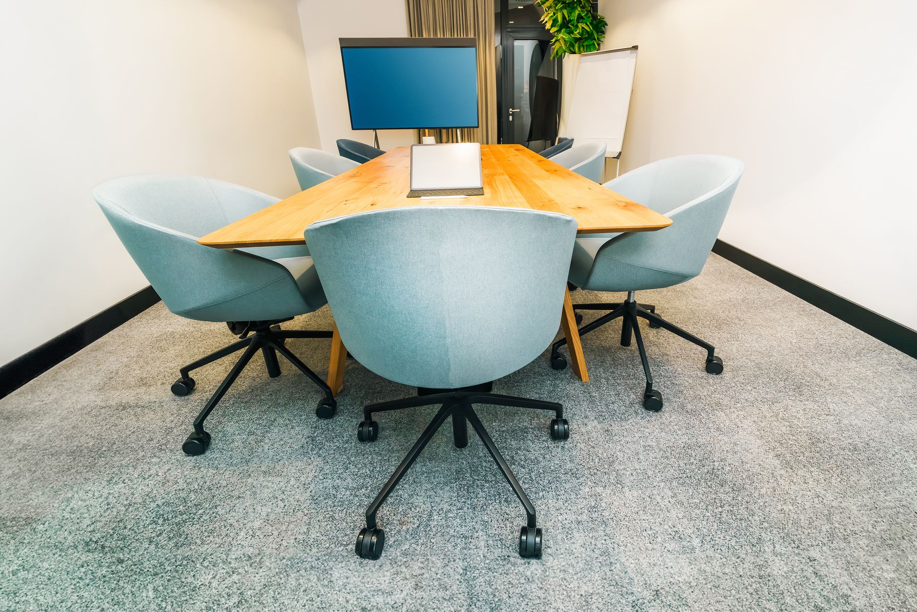 Empty modern conference room with sleek black chairs and wooden desks, perfect for business meetings.