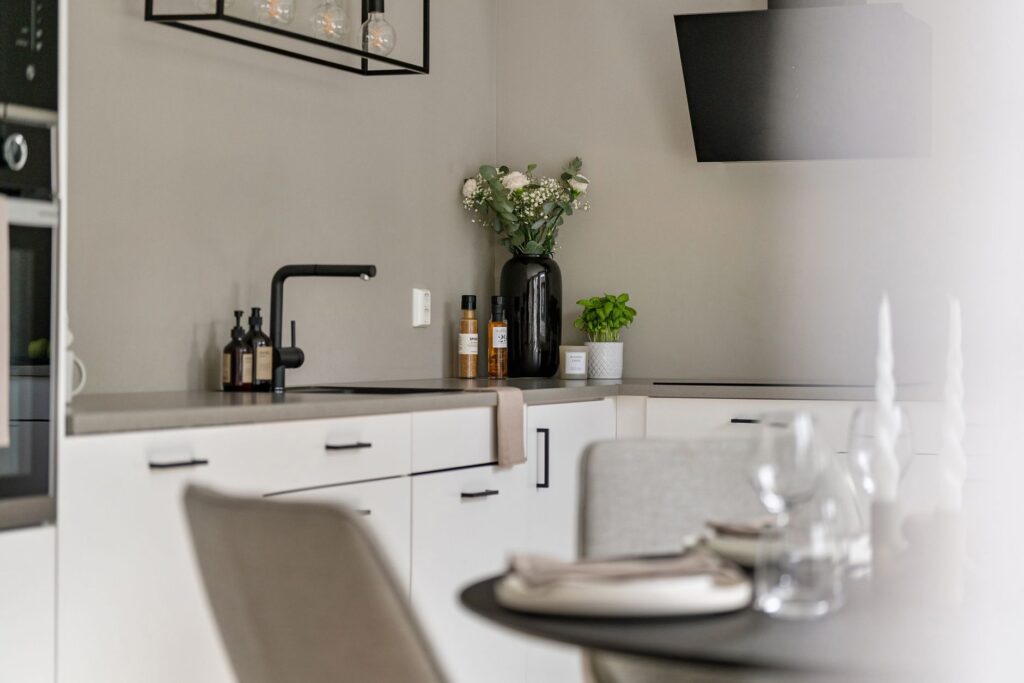 Sleek minimalist kitchen interior featuring decor, white cabinets, and contemporary appliances.